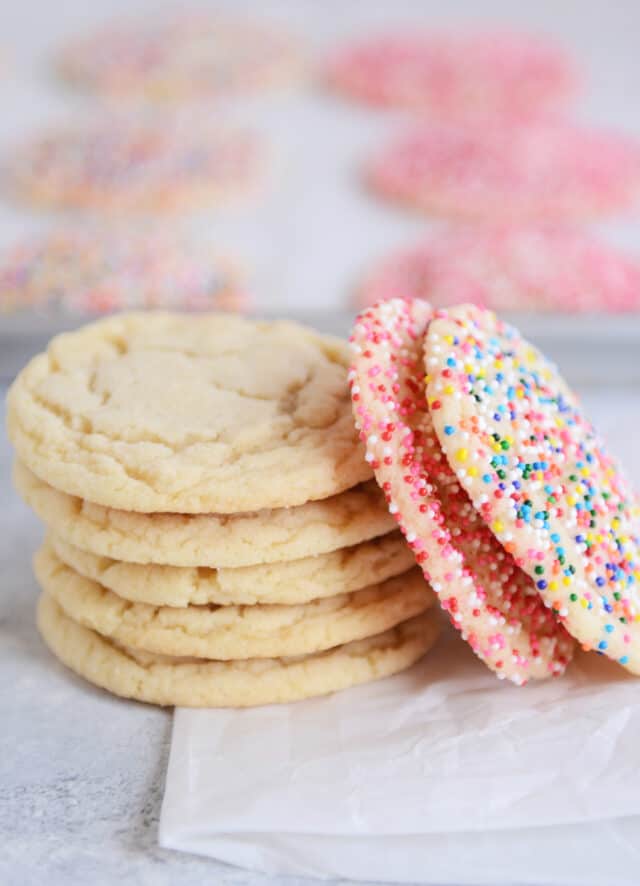 Five stacked sugar cookies on parchment paper.
