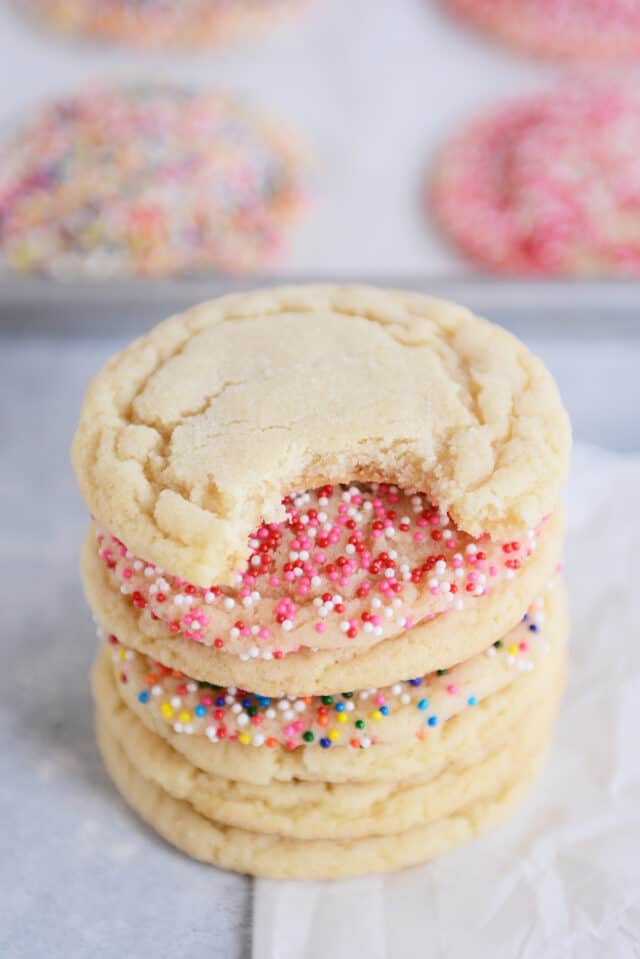 Sugar cookie with bite taken out stacked on top of sugar cookies.