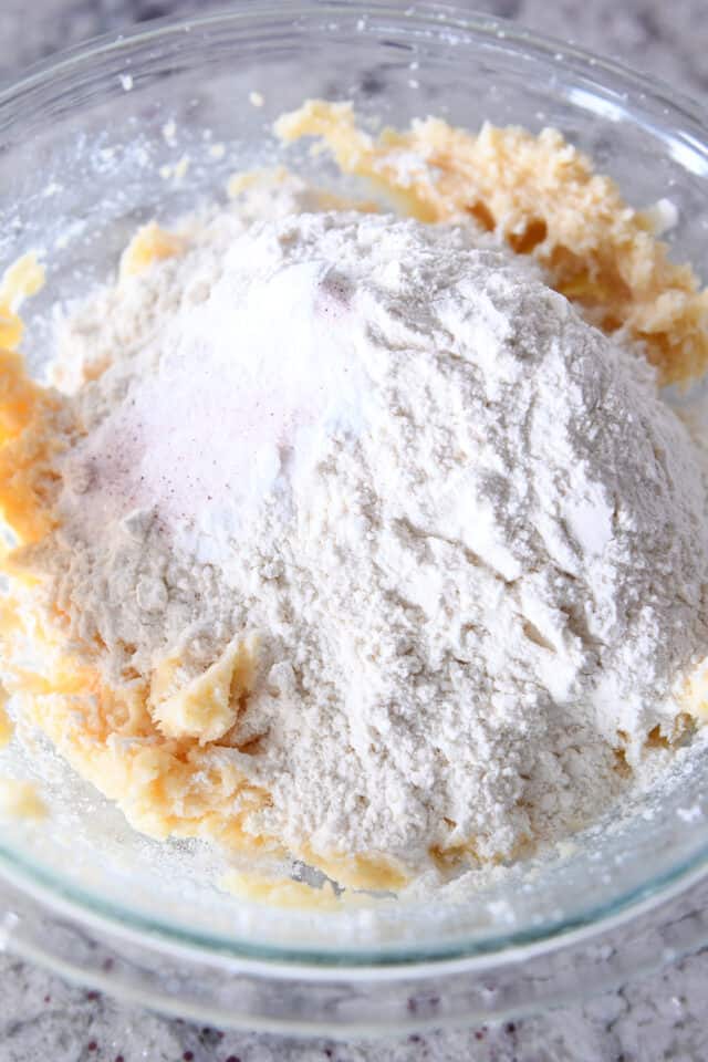 Glass bowl with sugar cookie dough and flour.