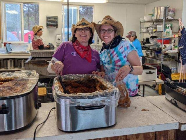 Two women in cowboy hats smiling for camera.