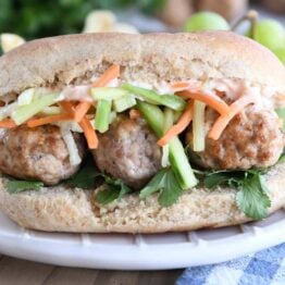 Banh mi meatball sub on cream plate.