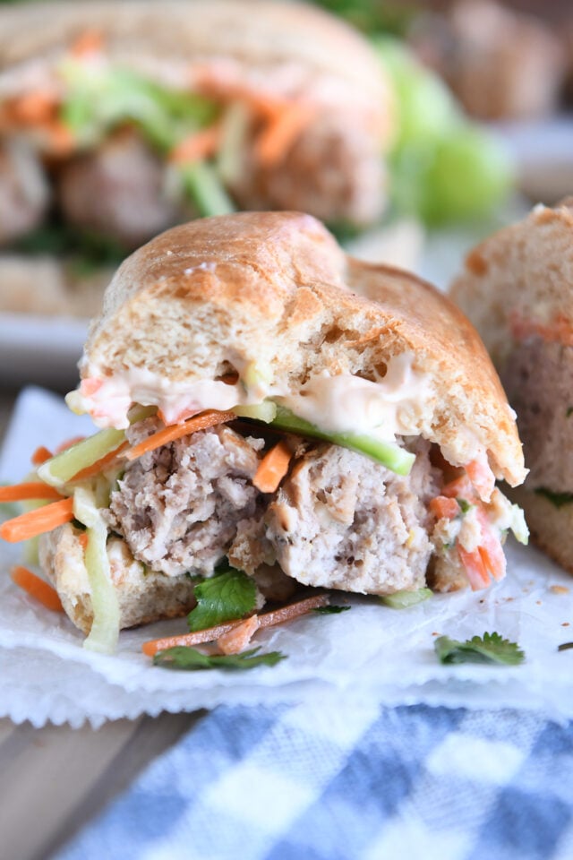 Half eaten banh mi meatball sub on parchment paper.