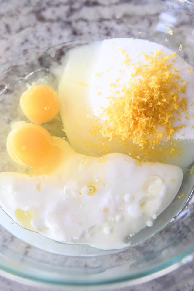Glass bowl with milk, eggs, lemon zest and sugar.