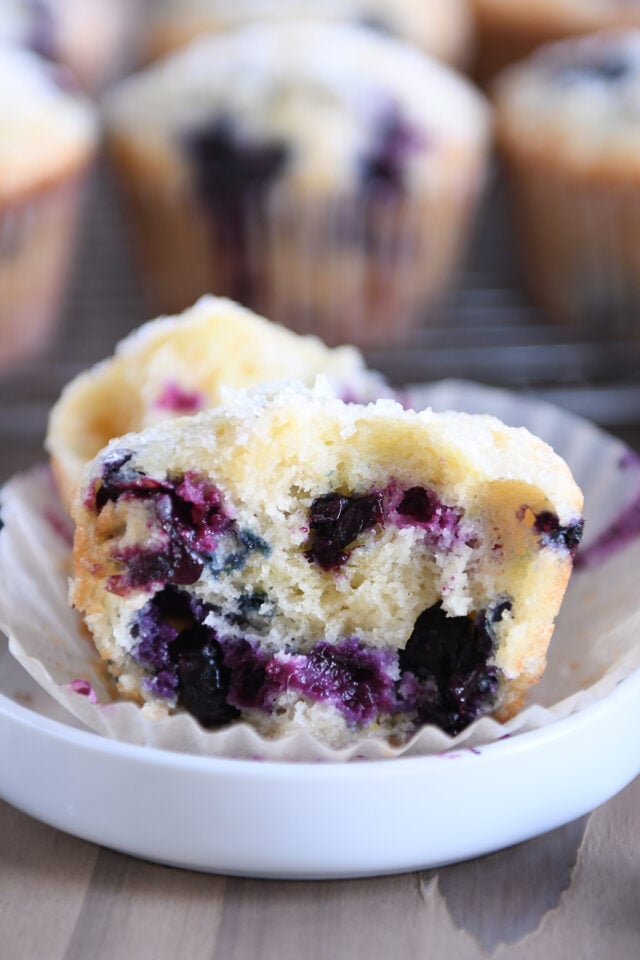 Half of a baked blueberry muffin on a small white plate.