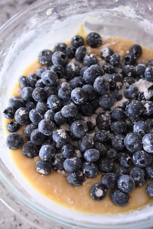 Floured blueberries in a bowl with the muffin batter.