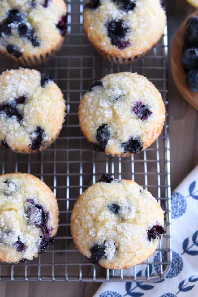 Six blueberry muffins on wire rack.