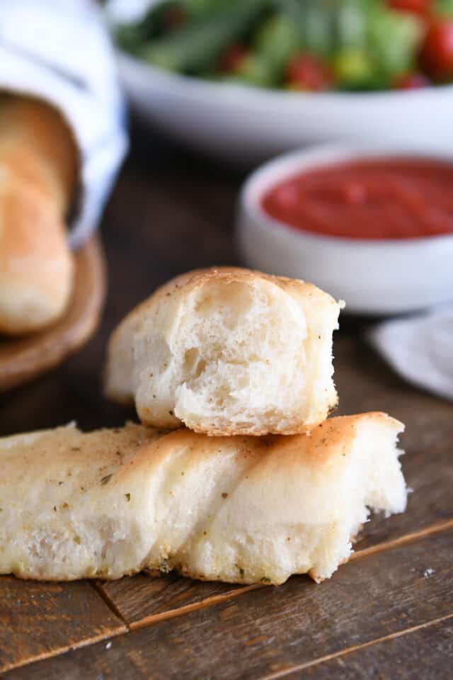 Breadstick in half on wood board.