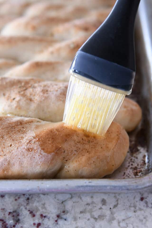 Brushing butter on homemade breadsticks.