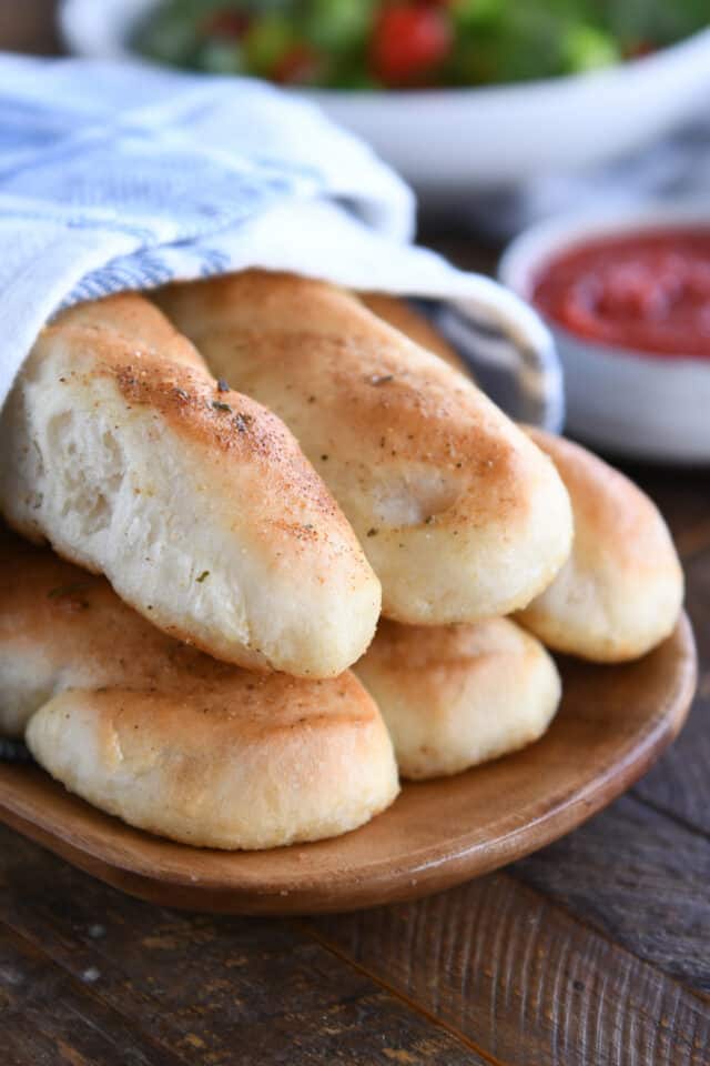 Five breadsticks on wood board.