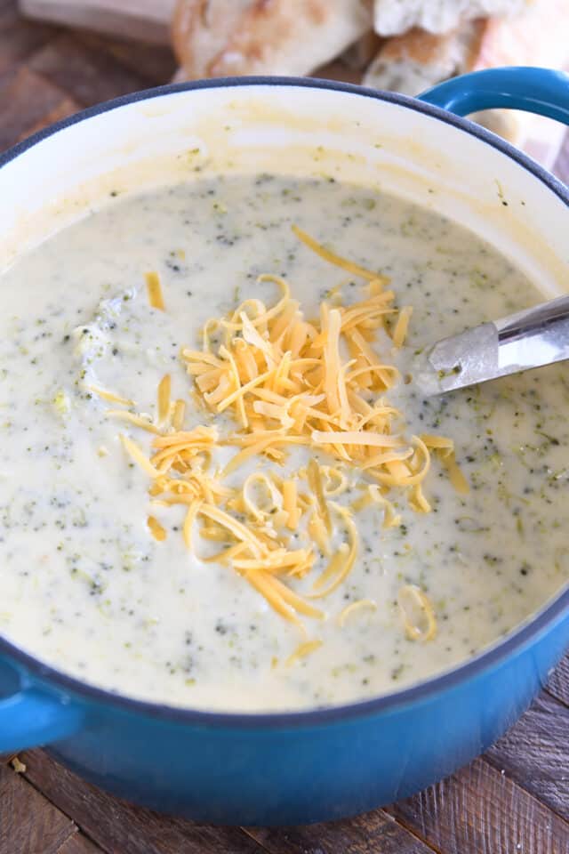 Broccoli cheese soup with shredded cheese in blue pot.