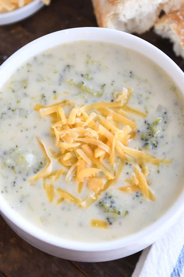 Broccoli cheese soup with shredded cheddar in white bowl.