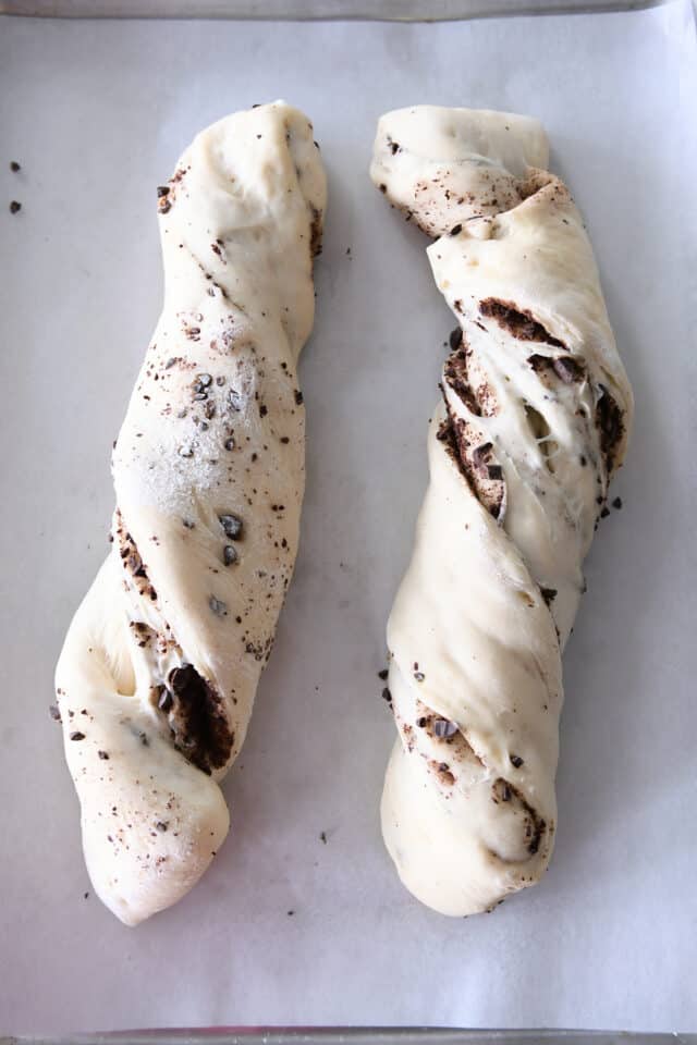 Two loaves of chocolate croissant French bread risen on sheet pan.