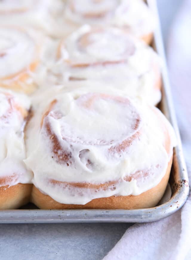 Baked and frosted cinnamon roll on sheet pan.