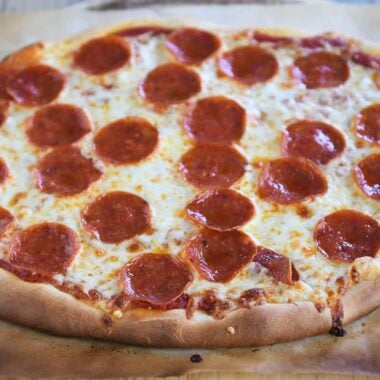 Baked pepperoni pizza with a golden crust on parchment paper.