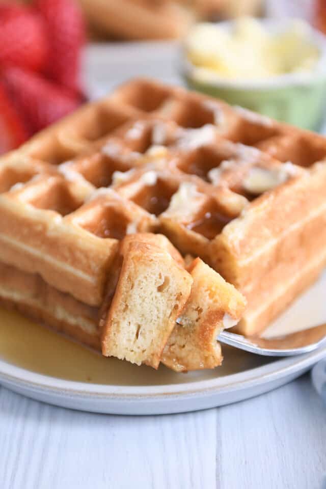 Fork with double stacked bite of waffles on gray plate.