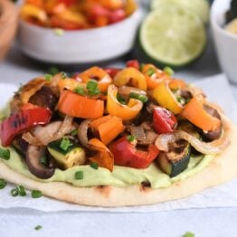 Flatbread topped with creamy avocado sauce and roasted vegetables.