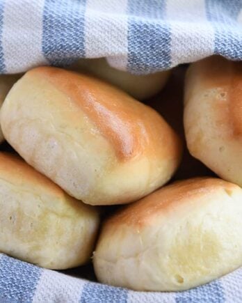 Five square rolls in basket with blue and white towel.