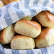 Five square rolls in basket with blue and white towel.