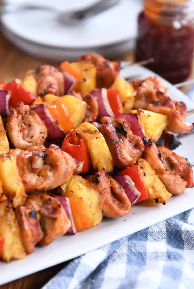 Four skewers of chicken, pineapple and onions on a white platter.