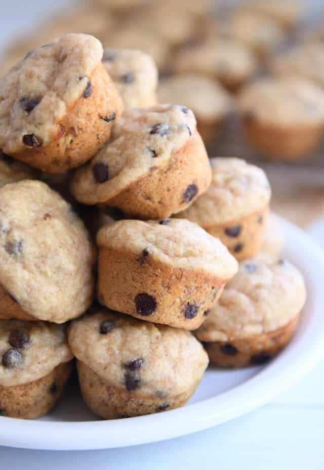Stack of mini banana chocolate chip muffins on white plate.