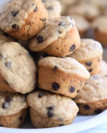 Stack of mini banana chocolate chip muffins on white plate.