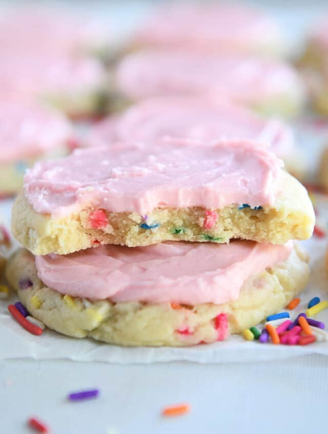 Sugar cookie broken in half on top of frosted sugar cookie.