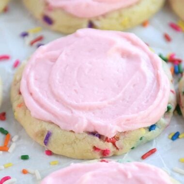 Pressed sugar cookies with sprinkles and pink frosting.