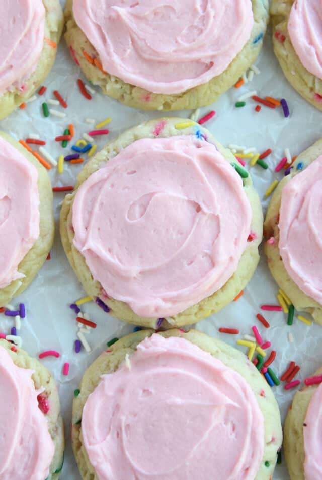 Top view of pressed sugar cookies with sprinkles and pink frosting.