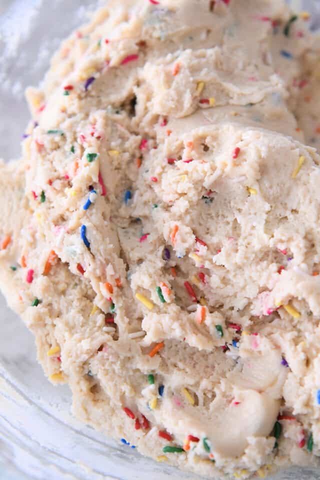 Sugar cookie dough with sprinkles in glass bowl.