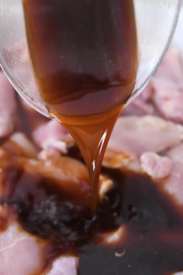 Pouring teriyaki marinade over chicken.