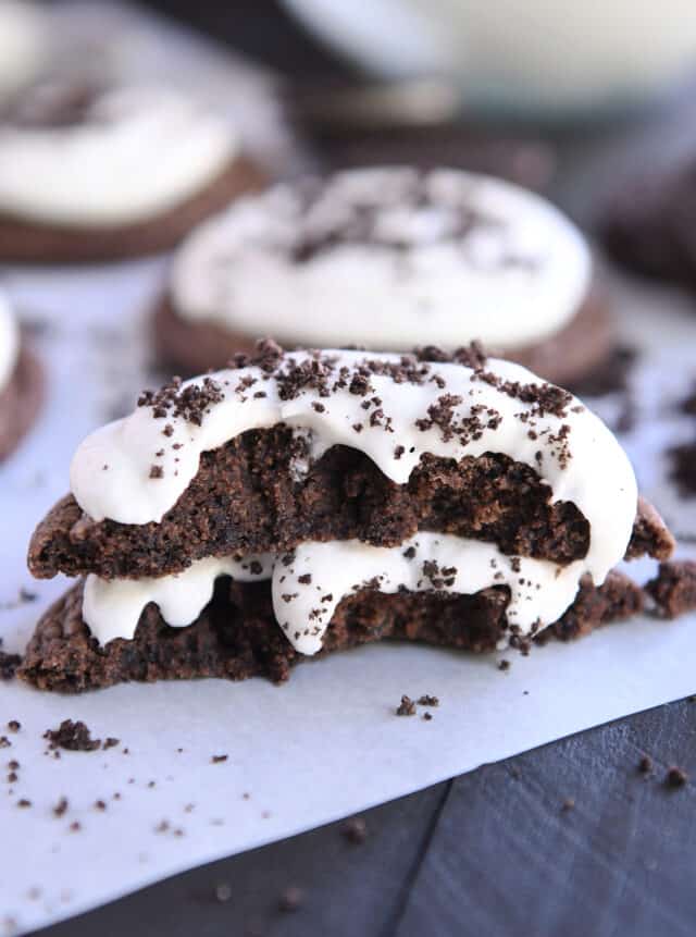 Oreo cookie broken in half and stacked on white parchment paper.