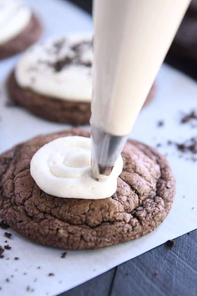 Piping frosting on top of Oreo crumbl cookie.