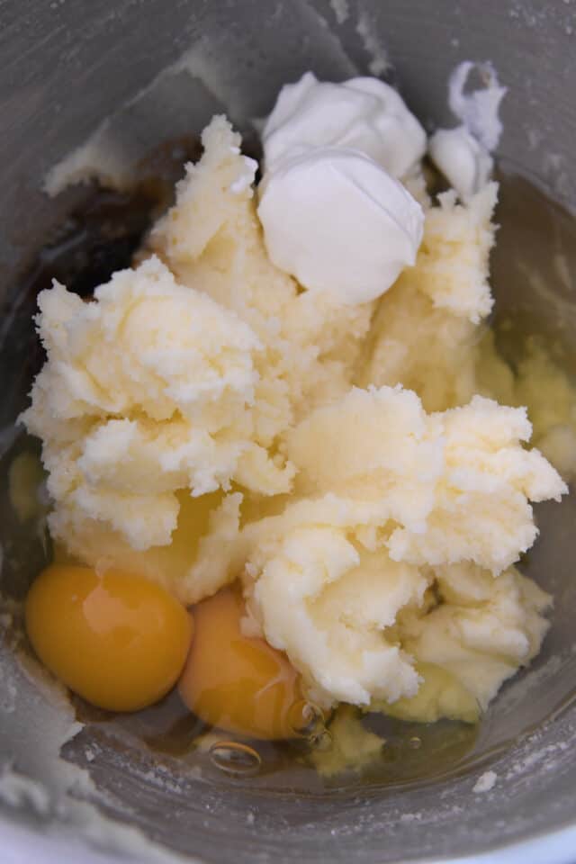 Bowl with eggs, creamed butter and sugar, and sour cream.