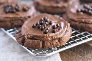 Frosted chocolate sugar cookie with chocolate pearls on metal rack.