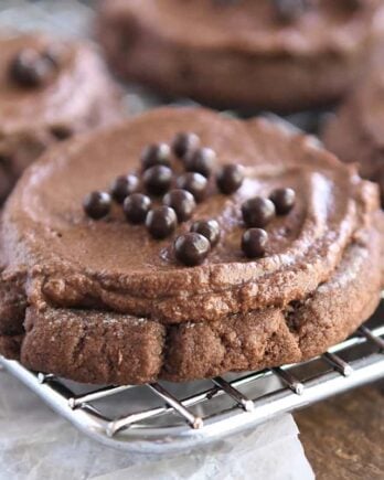 Frosted chocolate sugar cookie with chocolate pearls on metal rack.