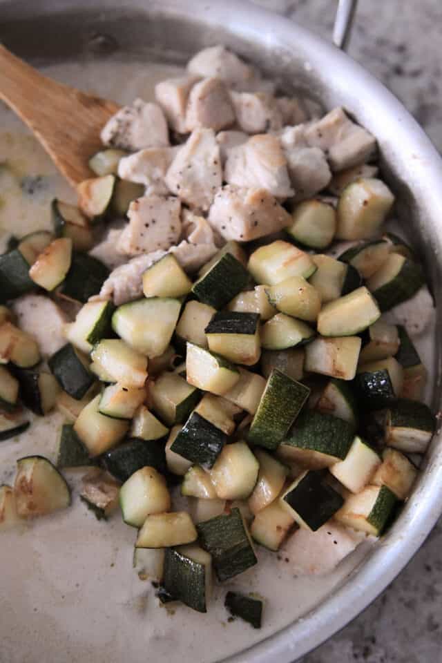 Chicken and zucchini in skillet with coconut cream sauce.