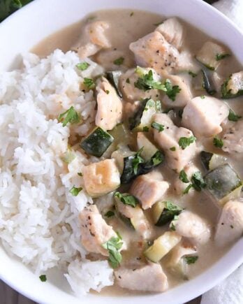 Top down view of chicken and zucchini in cream sauce over white rice.