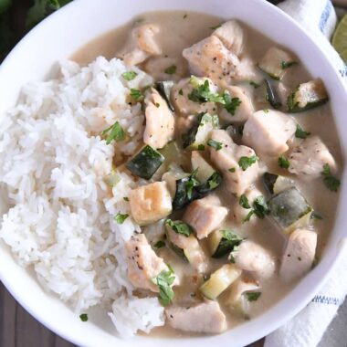 Top down view of chicken and zucchini in cream sauce over white rice.