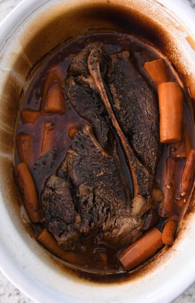 Cooked pot roast in slow cooker with carrots.