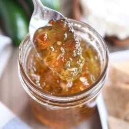 Spoon lifting up spoonful of jalapeno hot pepper jelly.