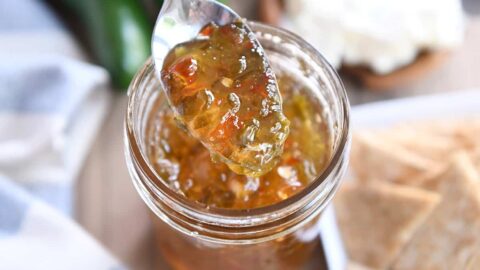 Spoon lifting up spoonful of jalapeno hot pepper jelly.