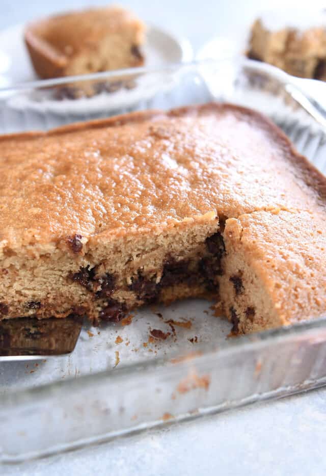 Glass square pan with baked chocolate chip cake with a few slices removed.