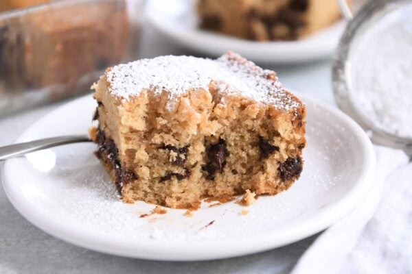 Half the edible chocolate chip cake was dusted with powdered sugar on a white plate.