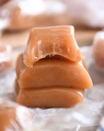 Three apple cider caramels stacked on parchment.