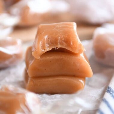 Three apple cider caramels stacked on parchment.