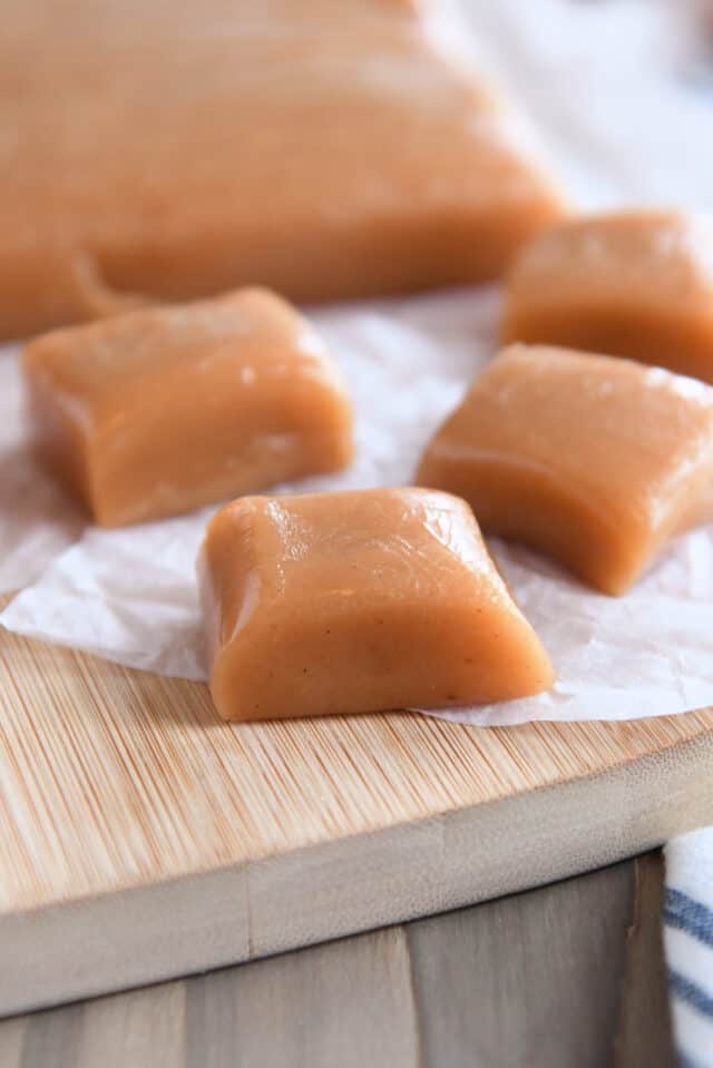Three squares of apple cider caramels on parchment paper.