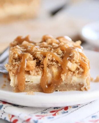 Caramel apple cheesecake bar on white plate with fork.