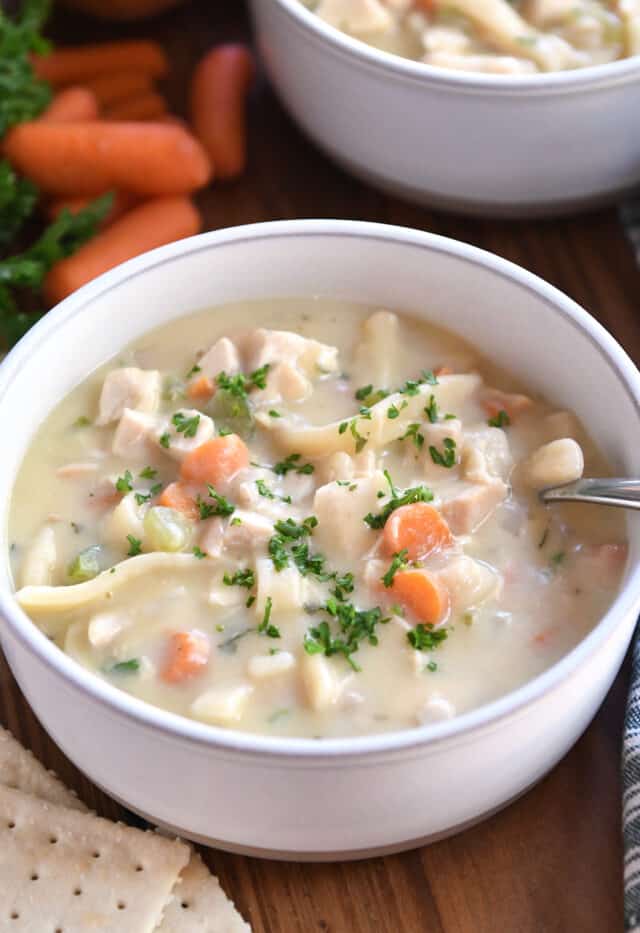 Spoon in bowl of creamy chicken noodle soup.