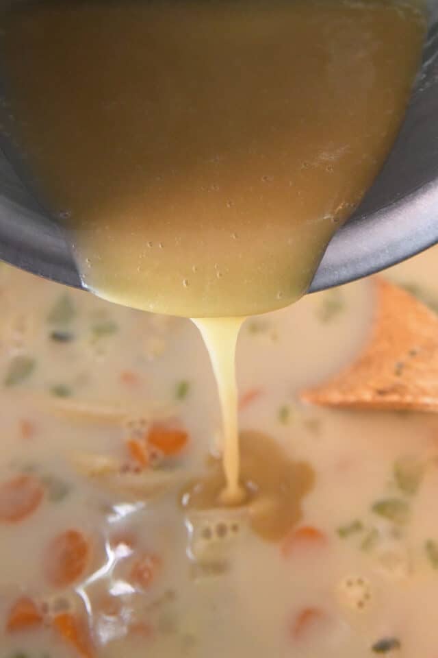 Pouring roux into chicken noodle soup.