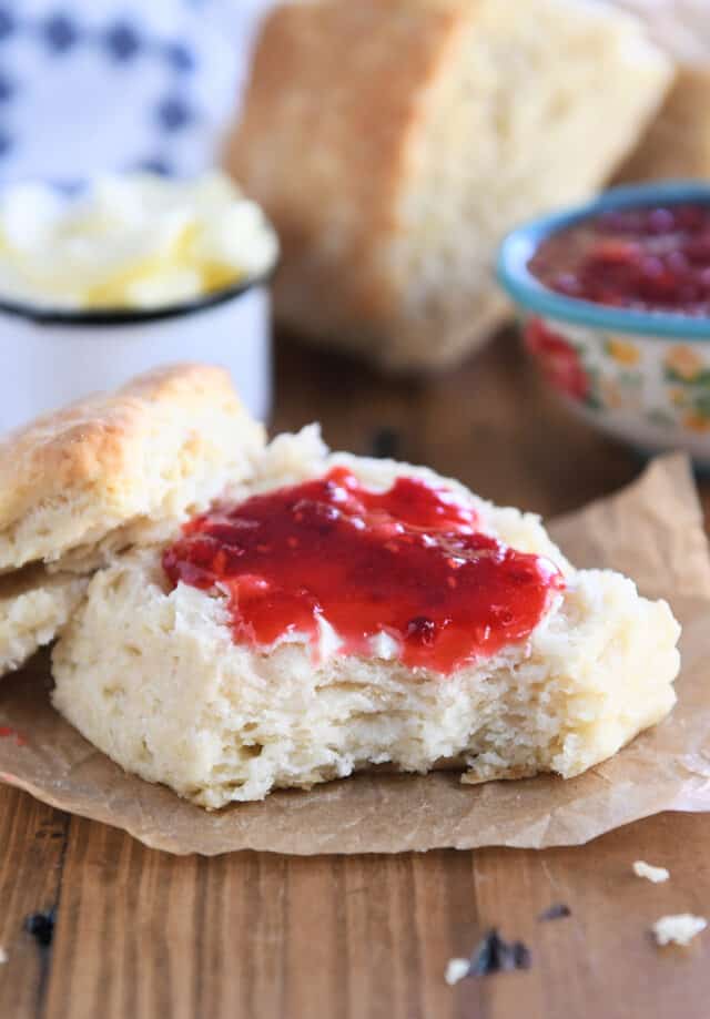 Half sourdough biscuit with butter and raspberry jam.